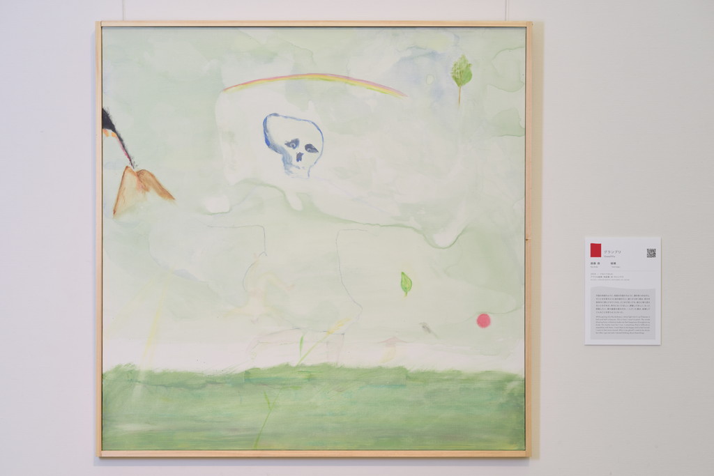 絵画作品の全体写真。中央に骸骨、その上に虹がかかり、左には噴火する火山、右下には赤いボールのようなものや、薄く描かれた人物などのモチーフが点在している